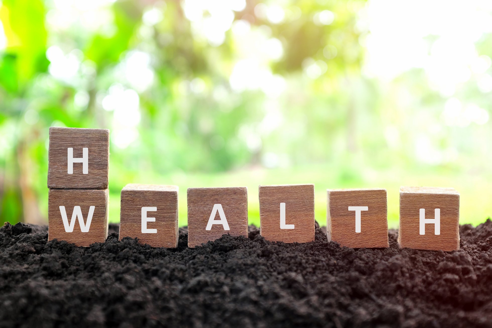 Health is wealth concept. Hand changing or flipping wooden blocks dice with word wealth to health in natural background.